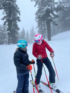 two people on skis standing in the snow