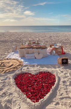 a heart shaped bed on the beach with food