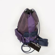 a purple and black bag sitting on top of a white table next to a tag