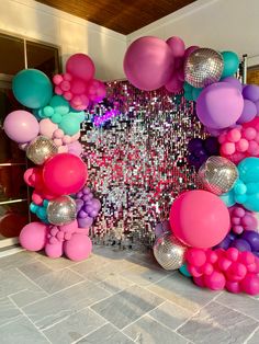 balloons and disco balls decorate the entrance to a party