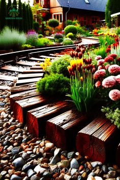 the garden is full of colorful flowers and rocks, along with wooden benches in front of it