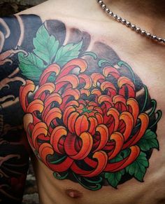 a close up of a man's chest with an orange flower tattoo on it