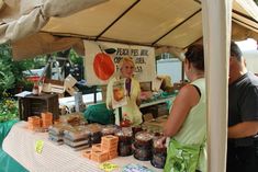 a woman standing at a table with jars of food in front of her and another person behind it