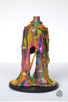 a multicolored vase sitting on top of a white table next to a black base