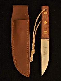 a knife and sheath sitting next to each other on a black surface with a white cord