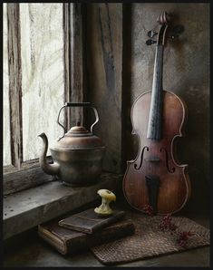 an old violin sitting on top of a table next to a vase