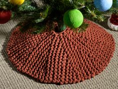 a knitted pot holder with balls on it and christmas tree ornaments in the background