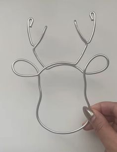 a hand holding a piece of metal wire that looks like a reindeer's head