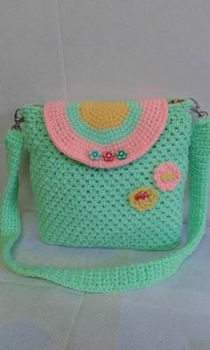 a crocheted purse with flowers and buttons on the front, sitting on a white surface