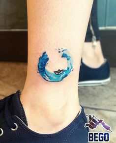 a woman's foot with a blue watercolor tattoo on her left side ankle