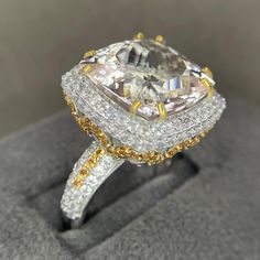 a fancy diamond ring with yellow and white diamonds on it's sides, sitting on a gray surface