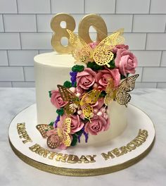 a birthday cake decorated with pink roses and gold butterflies for an 80th birthday party