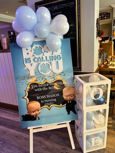 a sign with balloons attached to it in front of a display case for bob's calling you