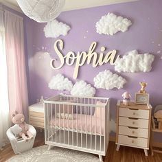 a baby's room with purple walls and clouds on the wall