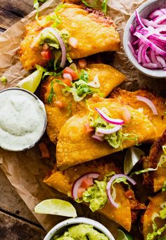 some tacos are sitting on a piece of wax paper with guacamole and salsa