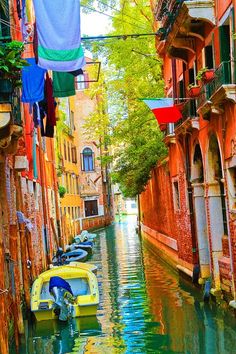 boats are lined up on the side of a narrow canal in an alleyway between two buildings