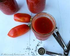 two jars filled with ketchup sitting on top of a table next to spoons