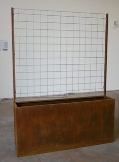 a wooden box with a grid design on the top and bottom, in front of a white wall