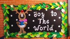 a bulletin board decorated with paper holly leaves and a reindeer holding a book in front of a brick wall