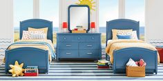 two blue twin beds in a bedroom with striped rugs and sun decorations on the wall