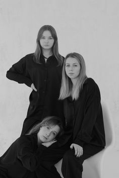 two women sitting on a white chair posing for a black and white photo with their arms around each other