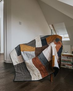 a quilt is draped on top of a chair in a room with wood flooring