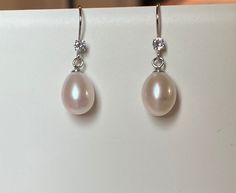 **DESCRIPTION**  - Sold as pairs. - This freshwater pearl dangle earrings come with 1 white freshwater pearl for each earring.  - Since it is handmade, every earring is not exact the same, as well as freshwater pearls.  - Good for daily wear or special occasions like weddings.    **MATERIALS** - The earring body is made with 925 stering silver. - 1 clear zircon and 1 freshwater pearl for each earring - Each freshwater pearl is slightly different in shape and size.  **PACKING AND GIFT WRAPPING** Hypoallergenic Oval Wedding Earrings, Hypoallergenic Oval Earrings For Wedding, Silver Earrings Wedding, Bridesmaid Gifts Earrings, Drop Earrings Silver, Pearl Earrings Wedding, Freshwater Pearl Earrings, Earring Gift, Freshwater Pearls Earrings