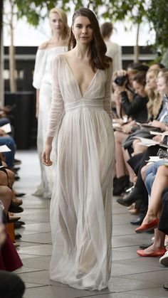 a woman walking down a runway in a white dress