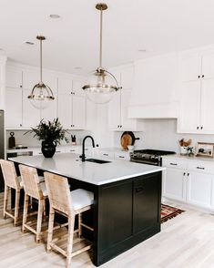 a kitchen with white cabinets and black island