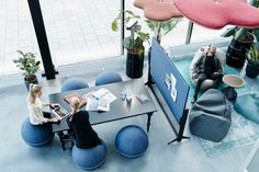 two people sitting at a table in an office setting with blue chairs and round tables