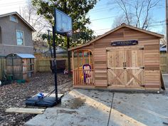 a backyard basketball court in front of a wooden shed with a basketball hoop on it