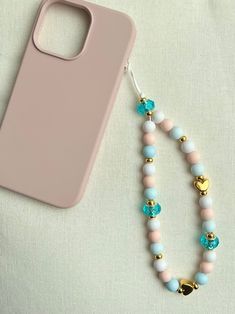 a cell phone case and some beads on a white surface with a pink iphone cover