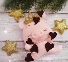 a stuffed pig laying on top of a wooden floor next to christmas tree branches and gold stars