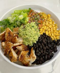 a white bowl filled with black beans, corn and guacamole next to lettuce