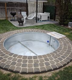 an empty hot tub sitting in the middle of a yard with chairs and tables around it