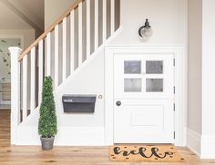 an entryway with a mailbox, plant and door mat in front of it