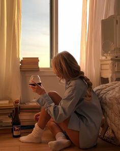 a woman sitting on the floor with a glass of wine