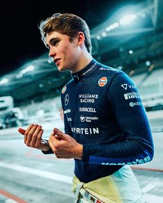 a man standing in front of a race track holding a cell phone