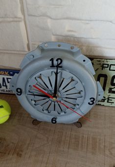 an alarm clock sitting on top of a table next to tennis balls and a license plate