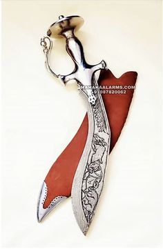 a knife that is on top of a piece of red paper with an ornate handle