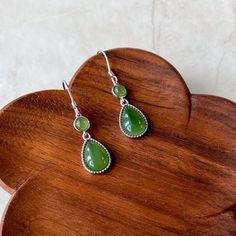 Stone Type: Nephrite Jade Metal: 925 Sterling Silver Earring Size (without hook): ~0.90 x 0.38 x 0.18 in. Drop Length: ~1.50 in. Earring Weight: ~3 g NATURAL JADE: This is a high grade jade earring. The stone is completely natural nephrite jade. DESCRIPTION: The "Forest Dew Drops"  earrings are inspired by the serene beauty of morning dew in the forest. Each earring features a perfectly polished, teardrop-shaped nephrite jade stone, cradled in a sleek sterling silver setting. Above the teardrop, a smaller round jade stone adds balance and harmony to the design. The verdant hue of the jade captures the essence of dew-kissed leaves, enhancing any outfit with its natural elegance. With secure and comfortable sterling silver hooks, these earrings are perfect for both everyday wear and special Jade Dangle Earrings, Morning Dew, Dew Drops, Nephrite Jade, Jade Earrings, Earrings Green, Natural Jade, Jade Stone, Silver Earring