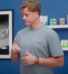 a man standing in front of a blue wall holding his hands out to the side