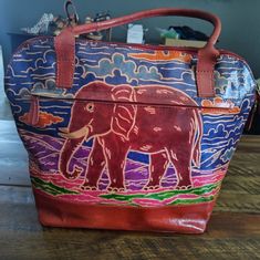 This Beautiful Genuine Leather Tote Is An Exclusive Hand Made Embossed Finish That Features A Beautiful Elephant Design. If You Love Elephants This Is Definitely A One Of A Kind Handbag That Is The Perfect Size For Everyday Use And Travel. The Bucket Shape Makes It Spacious And Has A Slip Pocket And A Zipper Pocket On The Inside. The Bag Also Has An Outside Zipper Pocket. The Lining Is Ivory Color And Pinstripe. This Bag Is A Beautiful Work Of Art! Elephant Embossed W: 15 1/2" H: 12" Bottom Widt Colorful Leather Shoulder Bag For Everyday Use, Purple Leather Handheld Shoulder Bag, Handheld Purple Leather Satchel, Handheld Purple Leather Shoulder Bag, Colorful Bags With Handles For Everyday Use, Large Capacity Purple Leather Bag, Colorful Everyday Bag With Handles, Colorful Travel Bags With Handles, Colorful Everyday Bags With Handles