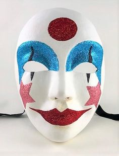 This handcrafted, full face, Venetian volto mask is decorated in shimmering sky blue, red, and rose pink glitter with a white painted face.  The mask is handmade from paper mache and measures approximately 9" high, 6 ½" wide and 3 ½" deep. The mask has traditional black ribbon ties for a comfortable fit.  All masks are handmade in Venice, Italy. No two masks are ever identical. Colors and patterns may vary slightly on each mask. Multicolor Full Face Carnival Mask, Fun White Masquerade Masks, Red Full Face Mask For Carnival, White Masquerade Mask For Carnival Festivals, Volto Mask, Stripe Mask, Costume Masks, Painted Face, Glitter Stars