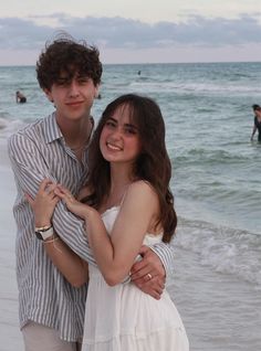 a young man and woman hugging on the beach