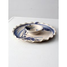 a blue and white porcelain dish with a spoon in the center on a white surface