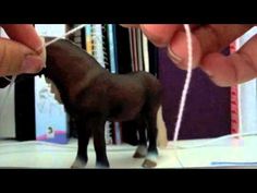 a person is stringing the tail of a toy horse on a table with books in the background