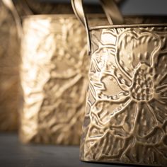 three gold vases sitting on top of a table next to each other with handles