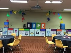 tables and chairs are set up in the middle of a room with colorful signs on the wall