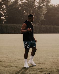 a man standing on top of a field holding a cell phone in his hand and wearing white socks